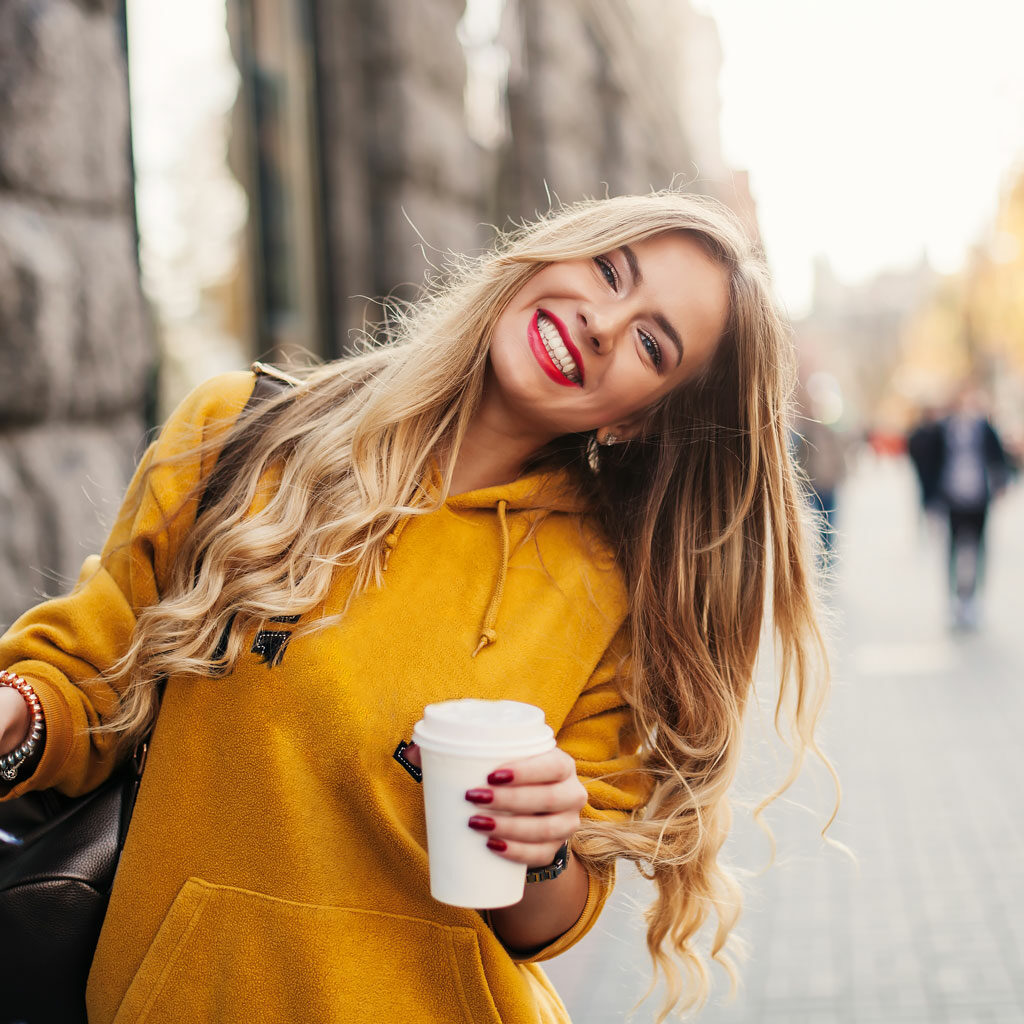 city girl wearing yellow jacket carrying coffee